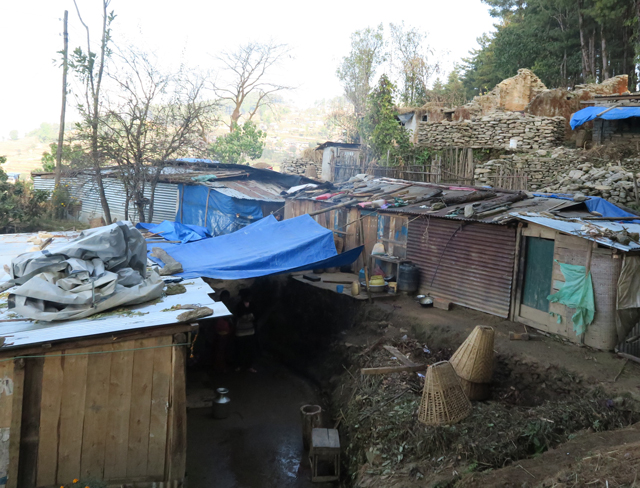 自力でなんとか作った仮設住宅。屋根が飛ばないよう重石をのせます。後方に写っているのは崩れたままの住宅